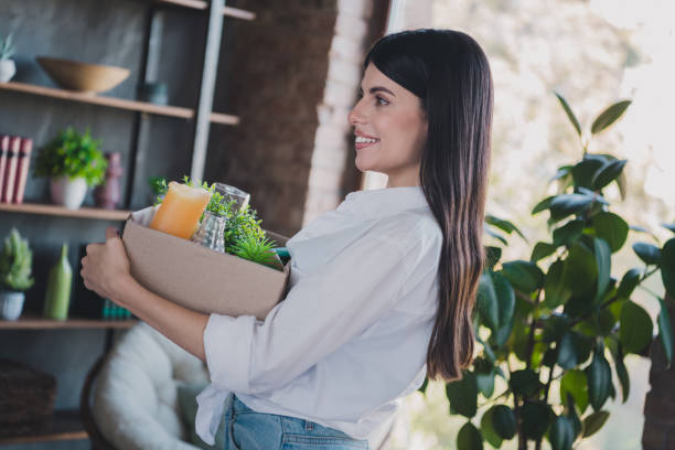 istock Young woman holding a box with home decor items in a bright and cozy interior 2193995503