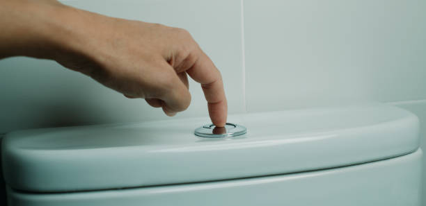 istock man flushing the toilet in a white-tiled bathroom 2193996728