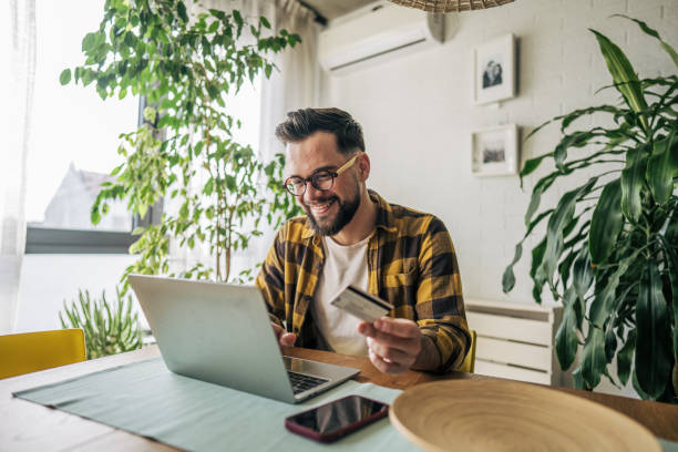 istock A man using his credit card while looking at his laptop in the dining room 2193997572