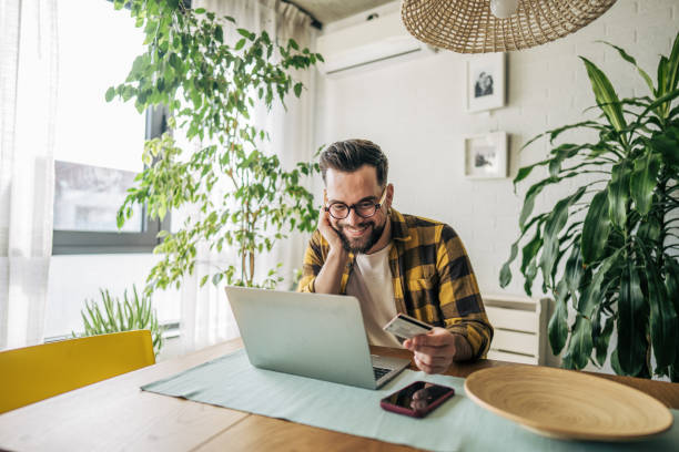 istock A man using his credit card while looking at his laptop in the dining room 2193997634