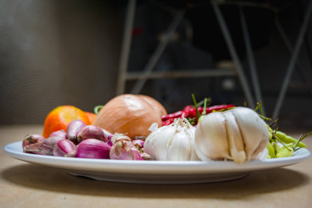 Horticultural herbs, tomatoes, chilies, shallots, garlic, onions on a plate