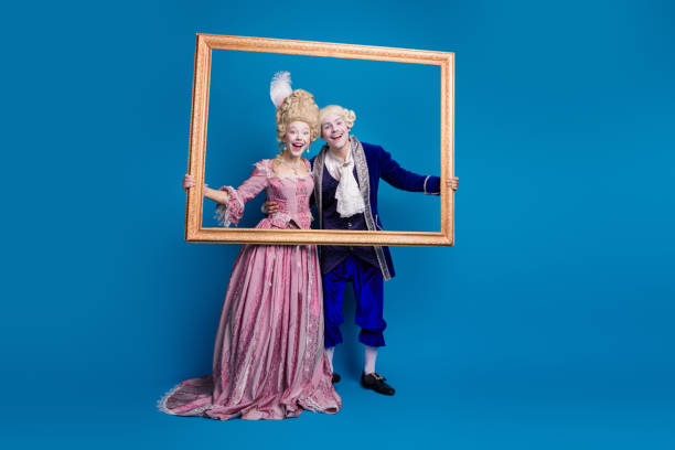 istock Two people in elegant historical costumes posing with a picture frame against a blue background 2193998086