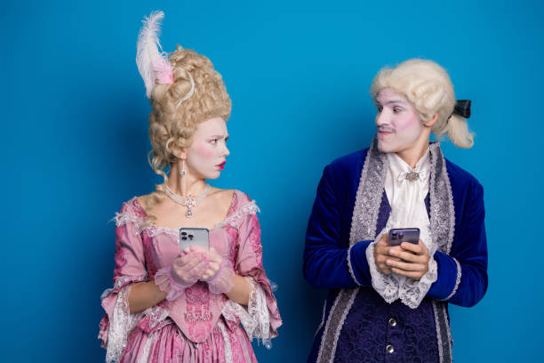 istock A whimsical couple in baroque attire texting on smartphones against blue backdrop, blending the elegance of the past with modern technology 2193998087