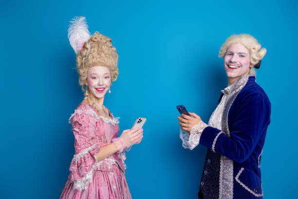 istock Cheerful young couple dressed in elegant baroque costumes poses amusingly against a vibrant blue background 2193998090