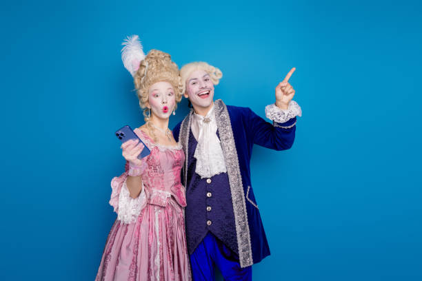 A playful couple dressed in baroque costumes interacts with modern technology, a humorous blend of historic fashion and present-day life