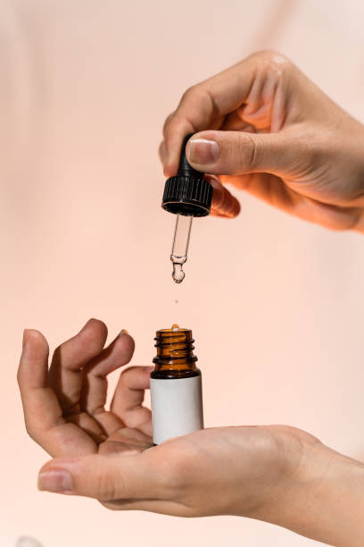 istock Hands holding pipette and opened dropper bottle with blank label over light beige, close up, mockup. Natural cosmetic, serum or essence. Everyday woman skincare routine 2194000705