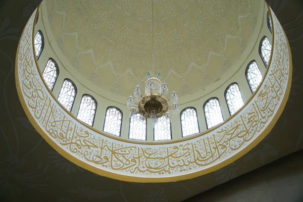 Elegant architectural details showcasing an intricately decorated Sheikh Zayed Grand Mosque dome featuring Islamic calligraphy, symmetrical windows, and a beautifully crafted central chandelier