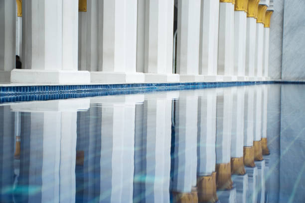 Captivating architecture featuring ornate pillars with golden trims, reflected beautifully in the calm pool, emphasizing traditional design and serene atmosphere