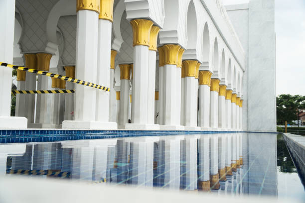 Beautiful Sheikh Zayed Grand Mosque architectural design displaying golden accents and symmetric columns, complemented by a tranquil water reflection