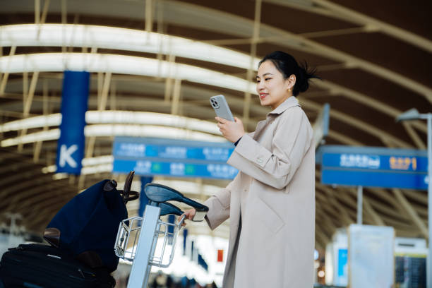 istock Asian young businesswoman with suitcase using smartphone while walking on moving walkway at airport terminal. Business traveller. Lifestyle and technology. Travel and vacation concept. 2194002568