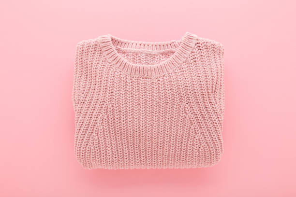 istock Folded knitted soft sweater on light pink table background. Pastel color. Closeup. Female wool warm clothes. Top down view. 2194005893