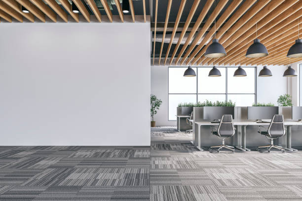 istock Semi-empty office interior with white wall and copy space,  a wooden slats ceiling, work desks and large windows, on carpet floor 2194011694