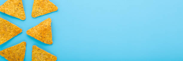 istock Yellow tortilla chips on light blue table background. Pastel color. Wide banner. Closeup. Empty place for text. Top down view. 2194011948