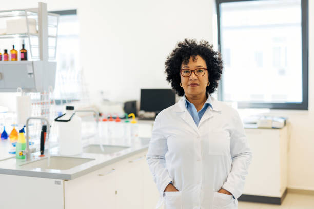 Portrait of a mature female scientist standing with her hands in her pockets in a modern laboratory, looking at the camera with a serious expression