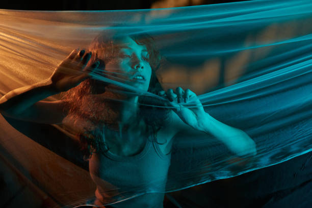 Tired female model trying to tear thin veil during photo shooting