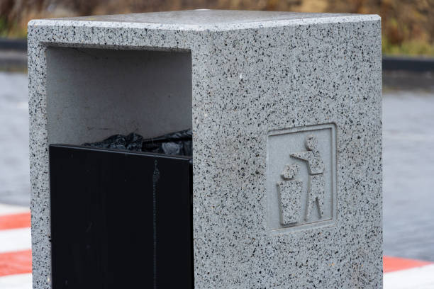 istock A concrete garbage container stands near water, promoting proper disposal of waste, including recycling and cigarette butts for clean surroundings 2194013886