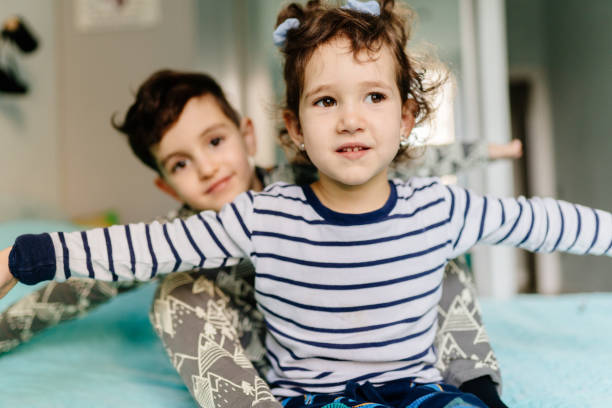 istock Two siblings playing together on a bed inside a cozy home 2194014456