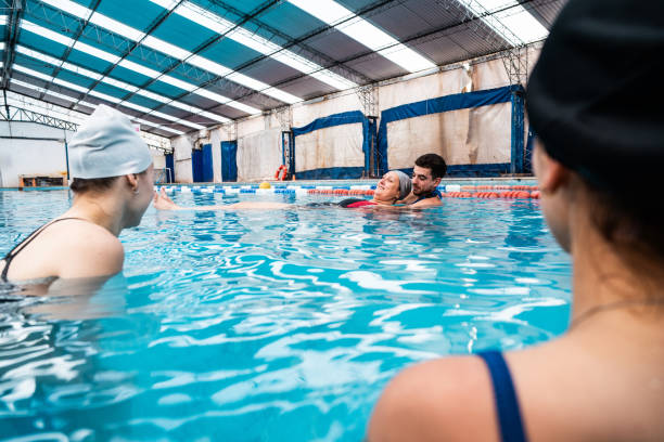 istock Lifeguard teaching swimmers rescue training on a swimming pool 2194020845
