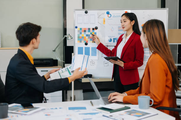 istock Group of professionals participating in meeting or workshop. presenter standing near flip chart give presentation interact with participants, attendee ask questions, share opinion or solutions. 2194021799