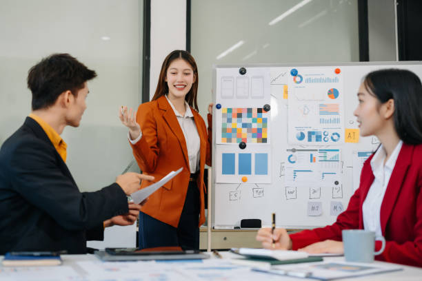 istock Group of professionals participating in meeting or workshop. presenter standing near flip chart give presentation interact with participants, attendee ask questions, share opinion or solutions. 2194021810