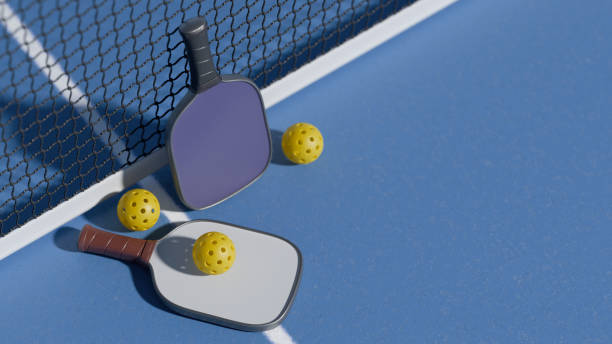 istock Two pickleball paddles and balls on a blue court, ready for play. 3d rendering 2194021912