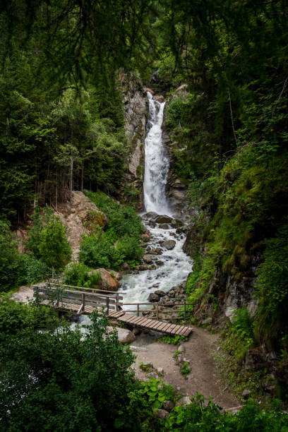 Large waterfall in the jungle with a wooden bridge over the river. Cascade du Dard