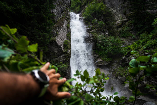 Hand removing weeds and showing a waterfall
