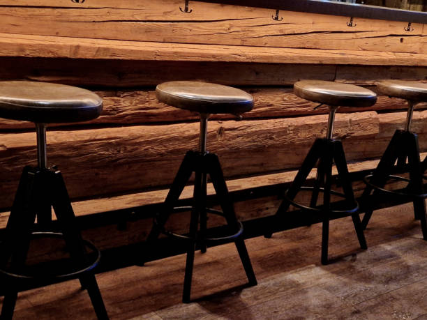 beams from an old barn front the restaurant's bar counter. leather padded covers for bar stools in the shape of a circle. backlight and hooks under the plate for coats and bags, handbags