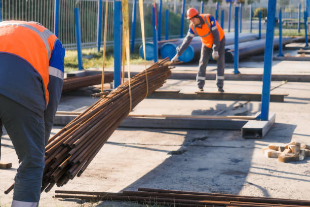 istock Construction workers handling metal pipes at outdoor worksite 2194029346