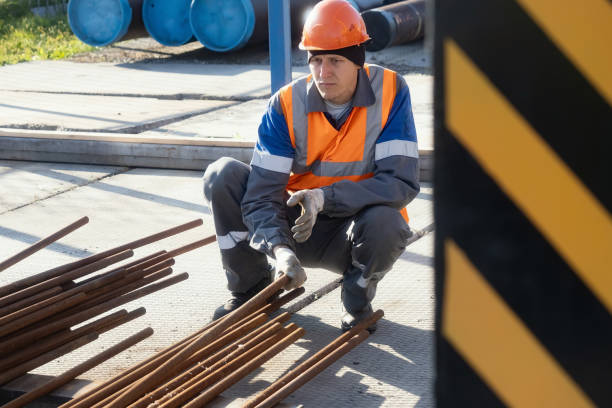 Male construction worker in safety gear arranging metal rods