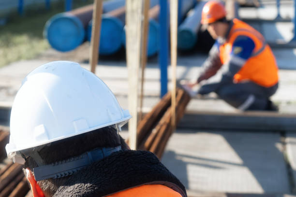 istock Construction site with workers in safety gear and equipment in focus 2194030846