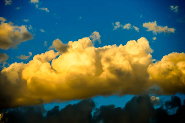 A large cloud in the sky with a blue sky behind it. The cloud is yellow and it looks like it is about to rain