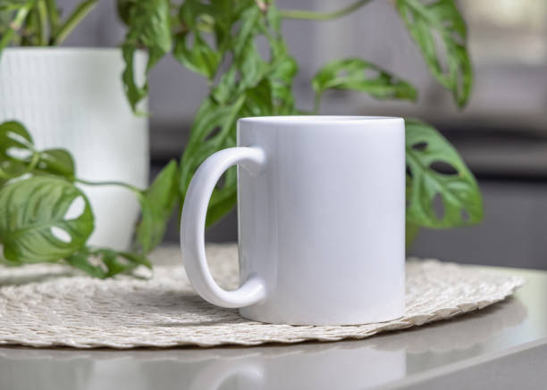 istock White blank coffee mug on grey table over blured green plant and kitchen interior, mockup 2194043584