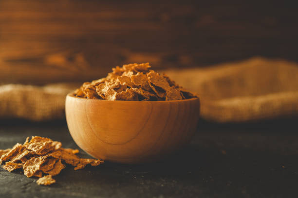 istock A wooden bowl filled with crunchy breakfast cereal flakes on a dark surface with rustic fabric in the background. Perfect for illustrating breakfast or healthy eating concepts 2194043920