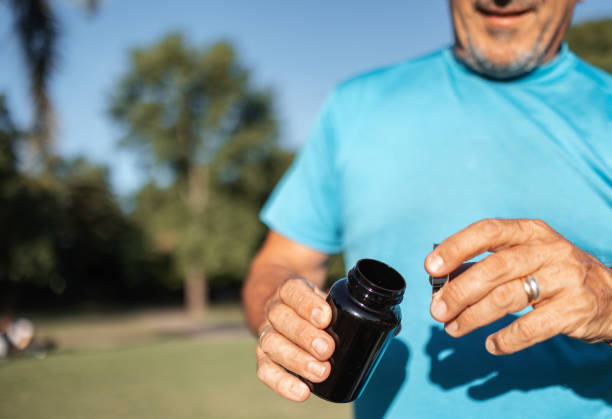 istock Man Opening a Supplement Bottle Outdoors in a Sunny Park 2194045187
