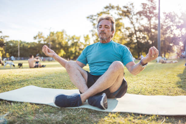 istock Mature man meditating on yoga mat in a sunny park setting 2194045216