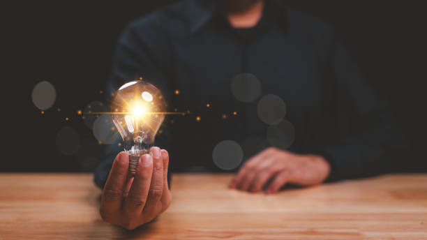 Person holds glowing light bulb, symbolizing innovation and creativity warm light radiates, creating an inspiring atmosphere image captures essence of fresh, bright ideas