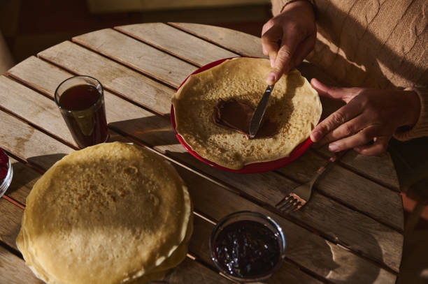 istock Hands spreading chocolate on pancakes with jam and drinks for a tasty treat 2194047276