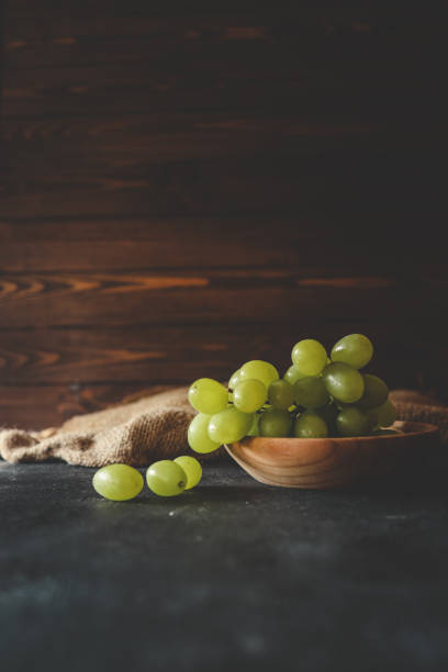 A bunch of fresh red grapes placed in a white bowl against a blue background, showcasing their vibrant color and juicy appearance.