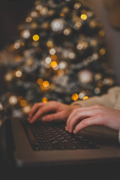 istock Hands typing on a laptop with a beautifully glowing Christmas tree in the background, creating a cozy and festive atmosphere indoors 2194048297