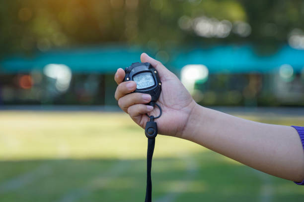 Coach holds a stopwatch to check the runners' speed statistics during practice. soft and selective focus.