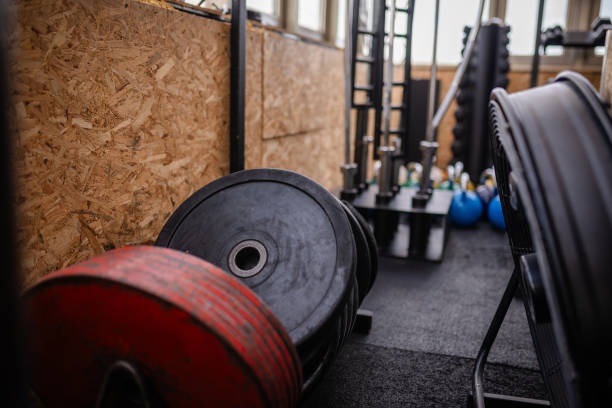 istock Black and red weight plates stacked on gym floor 2194049851