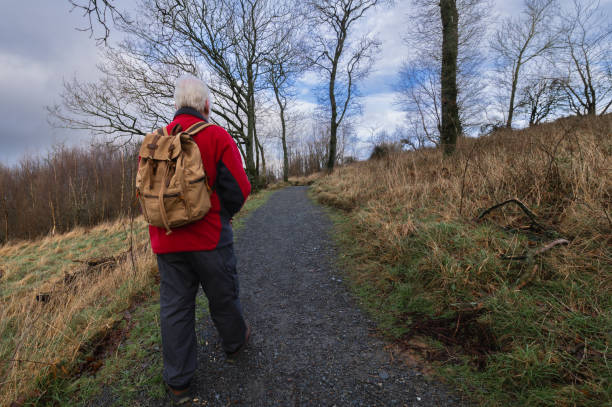 Retired man walking on a rural footpath on an overcast winter morning in Scotland