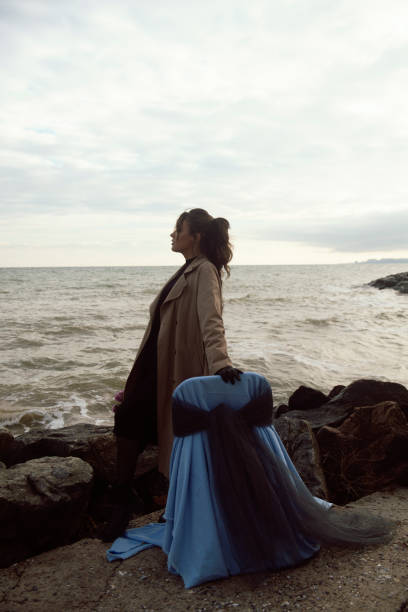 istock young girl on the seashore around the rocks 2194051143