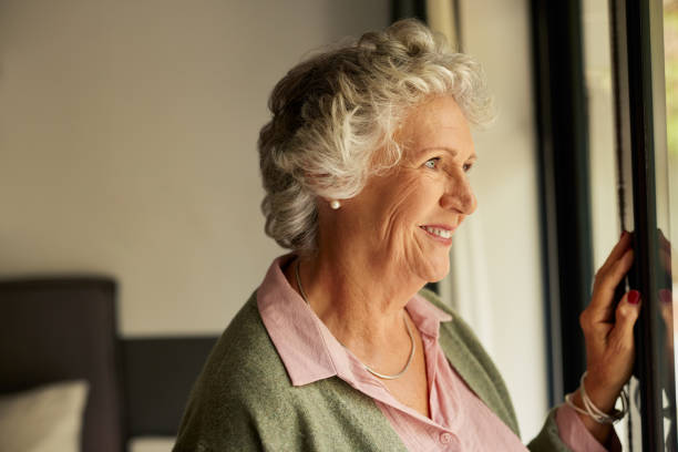 istock Senior smiling woman looking positive through the window 2194052049