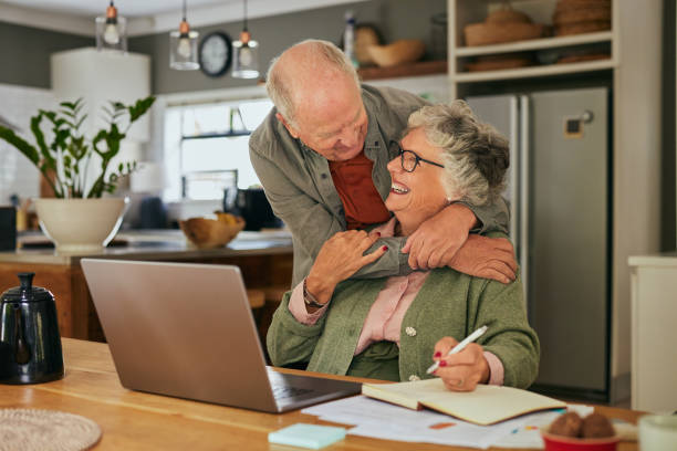istock Old man embracing his wife while working on laptop 2194053016