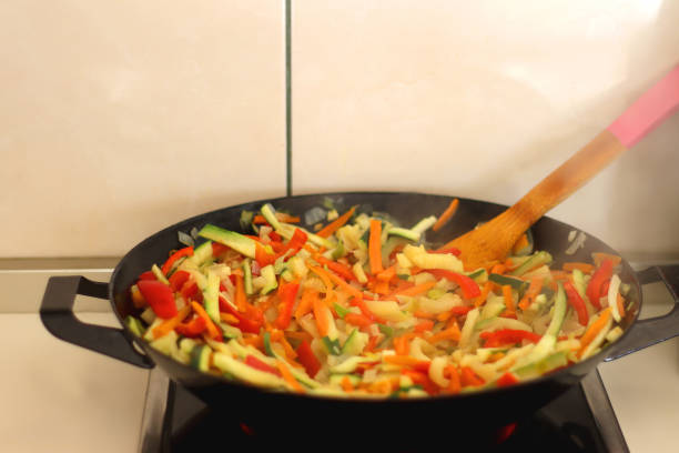 Stir frying chopped leek, zucchinis, carrots and red bell peppers in a wok. Selective focus.