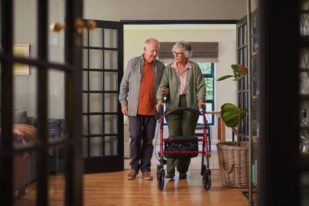 istock Senior husband helping old wife with medical walker 2194054596