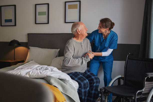 istock Smiling nurse assisting disabled senior man to get up from bed 2194054842