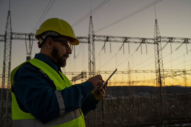 istock Engineer with tablet at an electrical power station checking equipment at sunset for maintenance. 2194055221